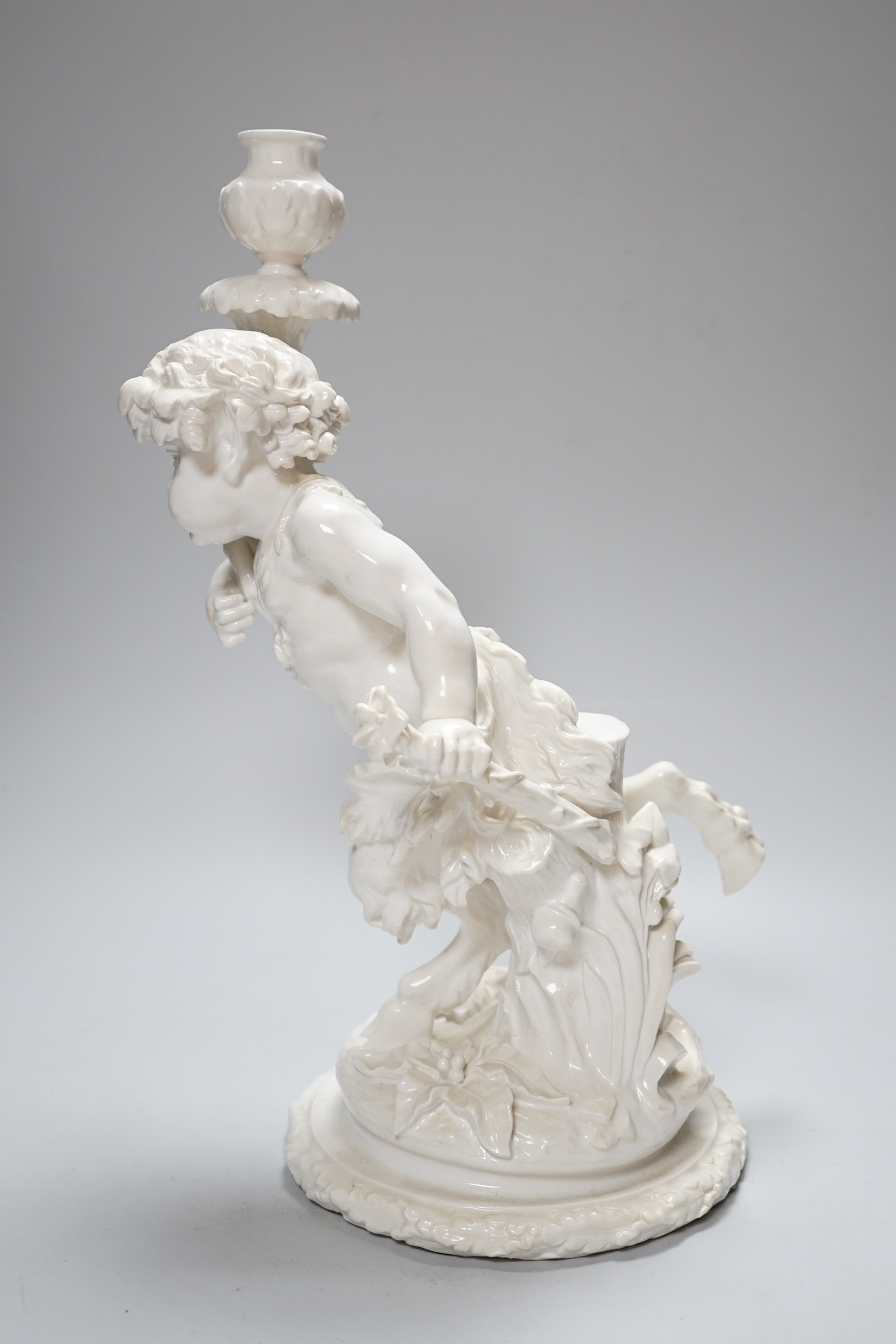 An English white glazed porcelain Bacchanalian fawn candlestick, possibly Moore Brothers, 39cm high